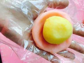 取冰皮，放于手中，按成圆形。将中间按压略薄些，边缘不用太薄哦，按照包蛋黄酥的手法，将馅料包裹进冰皮中