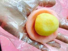 取冰皮，放于手中，按成圆形。将中间按压略薄些，边缘不用太薄哦，按照包蛋黄酥的手法，将馅料包裹进冰皮中