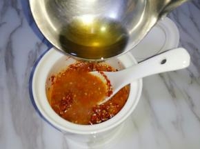 用铁勺舀适量油浇在辣椒粉上，快速搅拌均匀；分三次浇入菜籽油，搅拌均匀