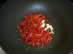 放入干红辣椒，蒜瓣，翻炒至呛鼻