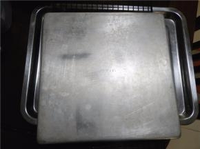 蛋糕烘烤至表面金黄色后取出，轻震一下，用脱模刀四周划一圈，表面垫上油纸后倒扣在网架上（如有油纸，迅速将蛋糕片连同油纸拖出烤盘，置于晾架上），表面再盖一张干净的油纸）。