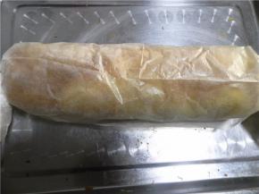 用擀面杖托于蛋糕片一端的油纸下，慢慢把油纸贴着擀面杖朝自己方向卷（压一压蛋卷的开头，定型），朝自己方向卷，同时推动蛋糕往前卷起来即可；卷好的蛋糕卷两头捏紧，放入冰箱冷藏半小时。