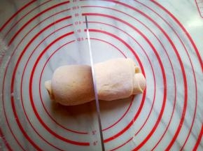 将卷好的玉米面面皮用刀从中间切开。