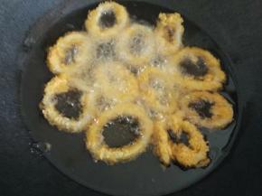 把锅擦干水份，倒入油烧到冒泡，鱿鱼圈一个个放入炸，炸至金黄色就可以捞起来了