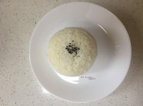 盘中装入米饭、少许芝麻点缀