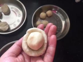 取一份水油皮拍扁，放入一个油酥。