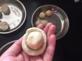 取一份水油皮拍扁，放入一个油酥。