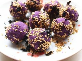 取一个紫薯球，按扁包入芝士片，再粘上芝麻和海苔碎。