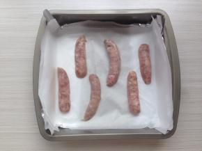 将香肠从中间剖开两半，放在铺了油纸的烤盘上（我这里是烤了3根香肠）