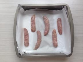 将香肠从中间剖开两半，放在铺了油纸的烤盘上（我这里是烤了3根香肠）