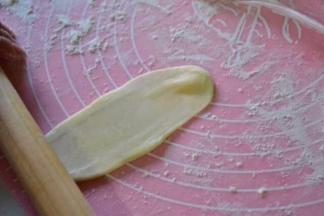 取一份醒好的酥皮面团，按扁擀成长椭圆形