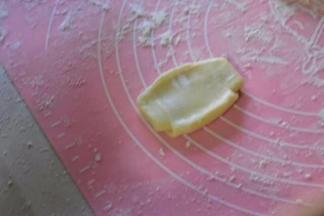 将面卷的接缝朝上，再次按扁，再次擀成椭圆形，再自上而下卷起来