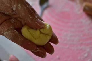 取出冰箱中的肉馅，拿一个醒好的面卷，将两头向中间折叠后按扁，用擀面杖将面皮擀成圆形