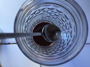 将勺子放在杯壁上，把一半的热牛奶沿着勺子向下倒