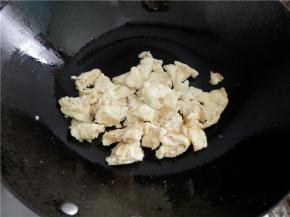 炒锅置电磁炉,锅中热花生油，倒入虾皮蛋液煎。再翻面煎，并炒散。