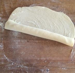 撒一些干粉，用擀面杖做芯把面皮卷起