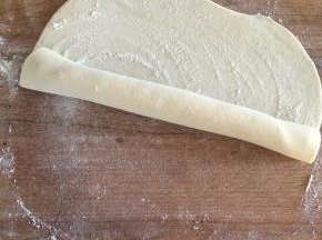 撒一些干粉，用擀面杖做芯把面皮卷起