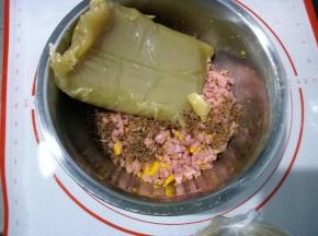 现在开始准备馅料。咸蛋黄提前解冻，烤肠直接用冻的，烤箱预热后，上火160度，下火140度，烤8-10分钟。晾凉蛋黄用勺子压碎，烤肠切块。放一个干净的盆里，然后放入50克自制肉松，250克低糖白莲蓉馅，总重量是480克。