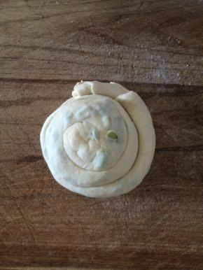 再把卷好的面团如图象蛇一样盘起来，拧成圆面团