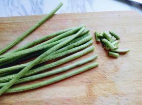 将长豇豆整齐的放在砧板上，切去根和尖。(切整齐，长短一致。)