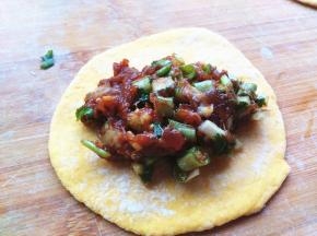 擀好的面皮，放入一勺肉馅，包好包子。