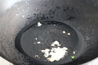 炒锅放油烧热，油温较高时，下入一半蒜末爆香。