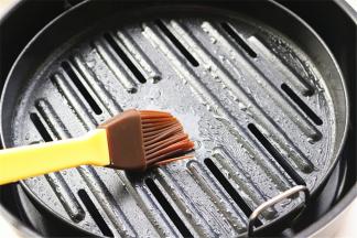 苏泊尔翻炸锅的烤篮里倒入少许油，用刷子刷开