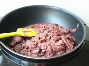 搅拌好的红豆沙倒入不粘锅里。