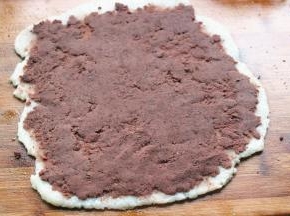 案板上抹一些油防粘，把年糕移到案板上，擀成均匀的薄片，上面抹上一层刚才炒好的豆沙，尽量抹均匀。