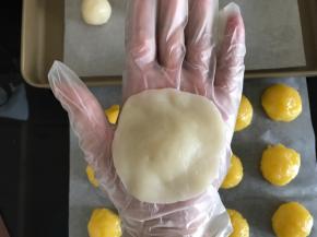 将冰皮压扁成中间厚周围薄的圆片，包上奶黄馅