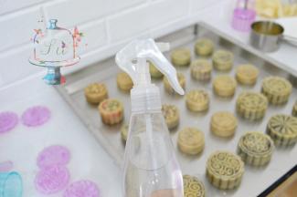 月饼全部按压好脱模之后，准备一个喷雾很细的喷壶。从高处薄薄的喷一层水雾在刚刚脱模好的月饼坯上。这样可以防止开裂。送入预热好的烤箱中层，温度转为200℃，烘烤5分钟