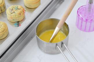 5分钟后出炉，，毛刷在容器壁刮去多余的蛋液，刷薄薄的一层在表面花纹上。一定不要贪多，蛋液多了月饼表面的花纹会变模糊。