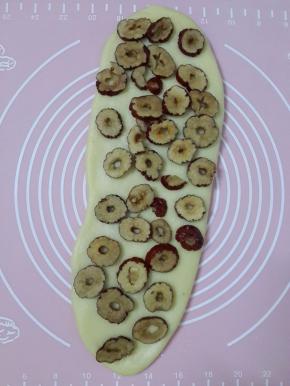 用擀面杖擀成锥圆形。然后均匀的铺上红枣片。