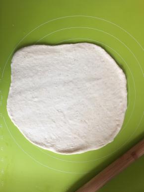 取出面团放在揉面垫上，揉面垫上可以撒一点高筋面粉，防粘，把面团擀扁排出气体，松弛15分钟