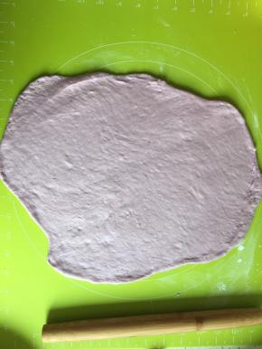 把面团放到揉面垫上，擀扁排出气体