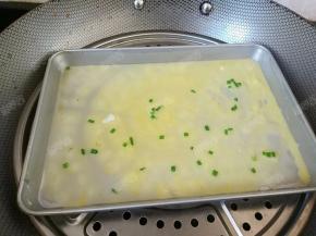 将肠粉盘左右晃动一下，让粉浆均匀的铺在盘子上，放入已经烧开水的锅中，盖上锅盖旺火蒸一分半钟