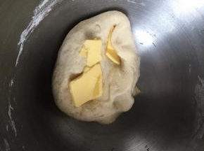 然后开始揉，揉到面团摸上去有点粘手但是不会粘下来面团，加入软化的黄油，继续揉