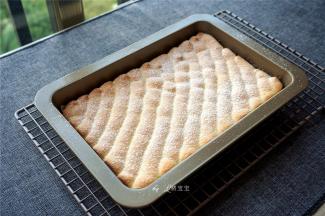 烤箱上下火185度预热，然后放入中层，烘烤12分钟左右取出，转移到冷却架上，并在表面撒上装饰用糖粉。冷却的过程，将淡奶油打发。