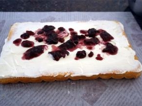 冷却至温温的状态时，将蛋糕倒扣出来，撕去底部的吸油纸，然后抹上淡奶油，铺上适量的蓝莓酱，再倒上剩余的全部淡奶油。