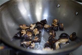 锅里加油微热将泡发的香菇下锅煎炒至出味。