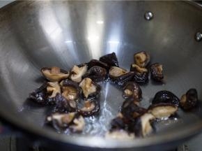 锅里加油微热将泡发的香菇下锅煎炒至出味。