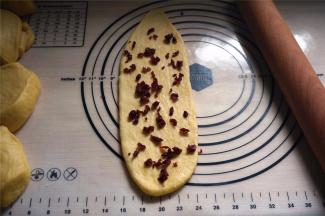 擀开成长舌状，撒上约8克的蔓越莓干，卷起。