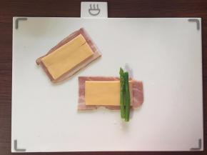 培根和芝士片对半切，取切好的培根片放上芝士片和芦笋，卷起收紧