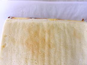 将蛋糕卷铺在虎皮蛋糕卷上，用刀呈45度角裁掉一侧的边角，这样卷到尾部的时候蛋糕不会太厚，会很平整的贴在卷起的蛋糕卷上