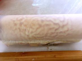 利用擀面杖将蛋糕卷卷起，之后在用擀面杖压一下，抽紧油纸，让蛋糕卷的紧实些，之后放冰箱冷藏半个小时