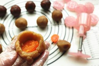 馅料按扁，包入蛋黄，整理成球状。