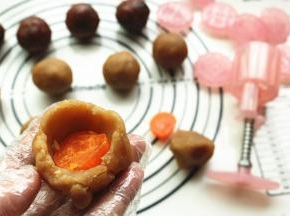 馅料按扁，包入蛋黄，整理成球状。