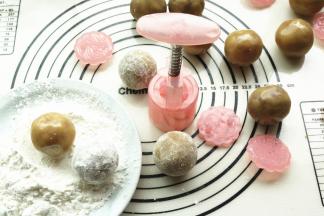 包好的月饼球，在生粉里滚一圈，然后再抖去多余的淀粉，月饼花片也在生粉里滚一下并抖干净粉。