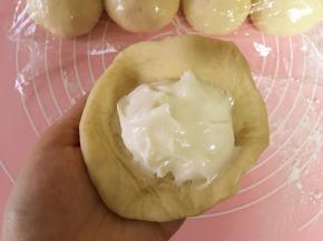 取出一个小面团，擀成中间厚四周薄的圆片，包入2勺乳酪馅，将接口处捏紧