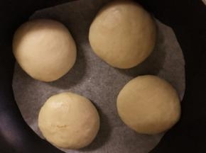 将包好的其中4个乳酪包放入平底锅中（锅内放一张油纸），盖上锅盖再发酵20分钟，剩余的4个乳酪包也放在油纸上盖上保鲜膜室温发酵
